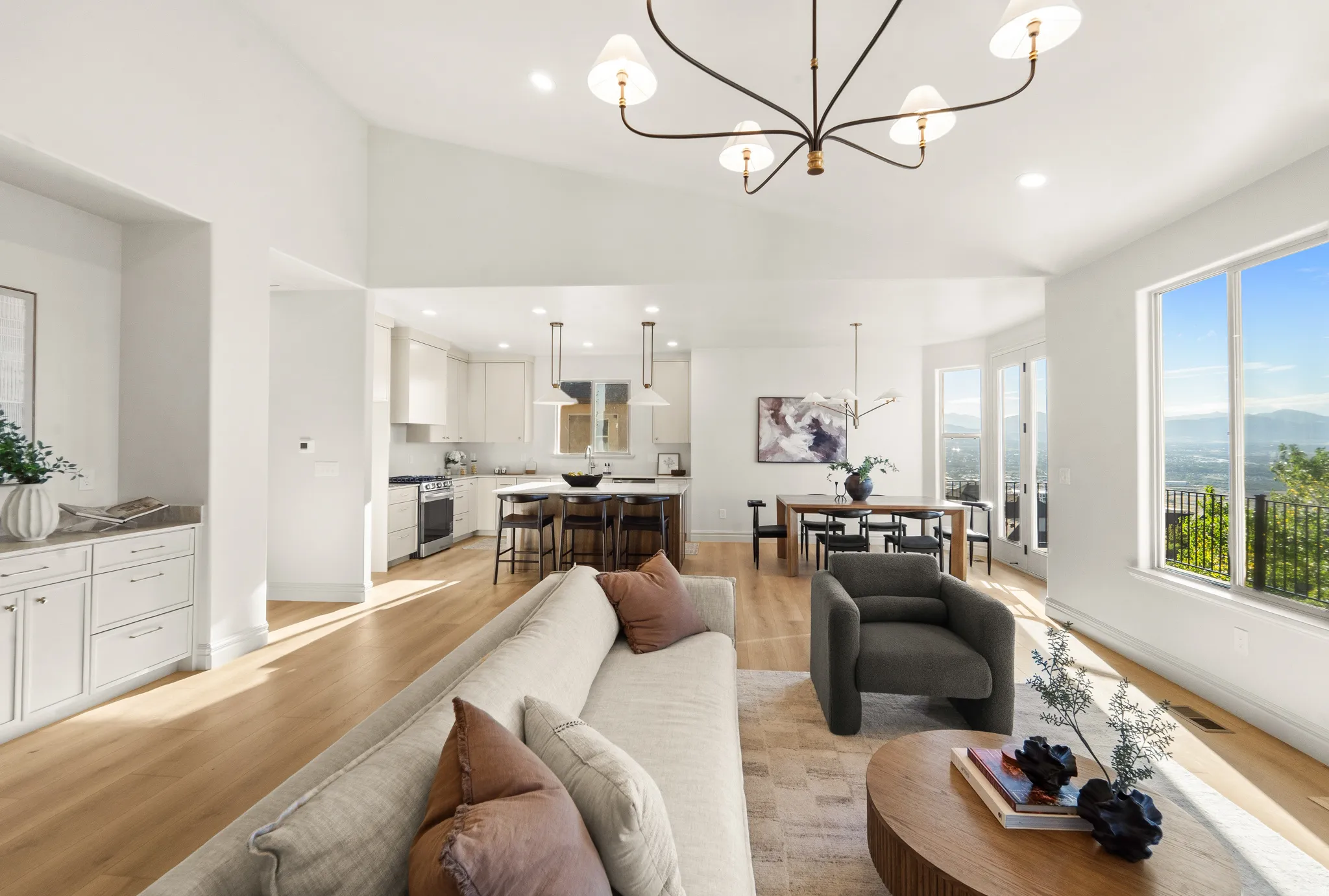 Vaulted ceilings with recessed lighting, wood-finish flooring, white cabinetry with built-in storage, and a large window providing expansive mountain and city scenery