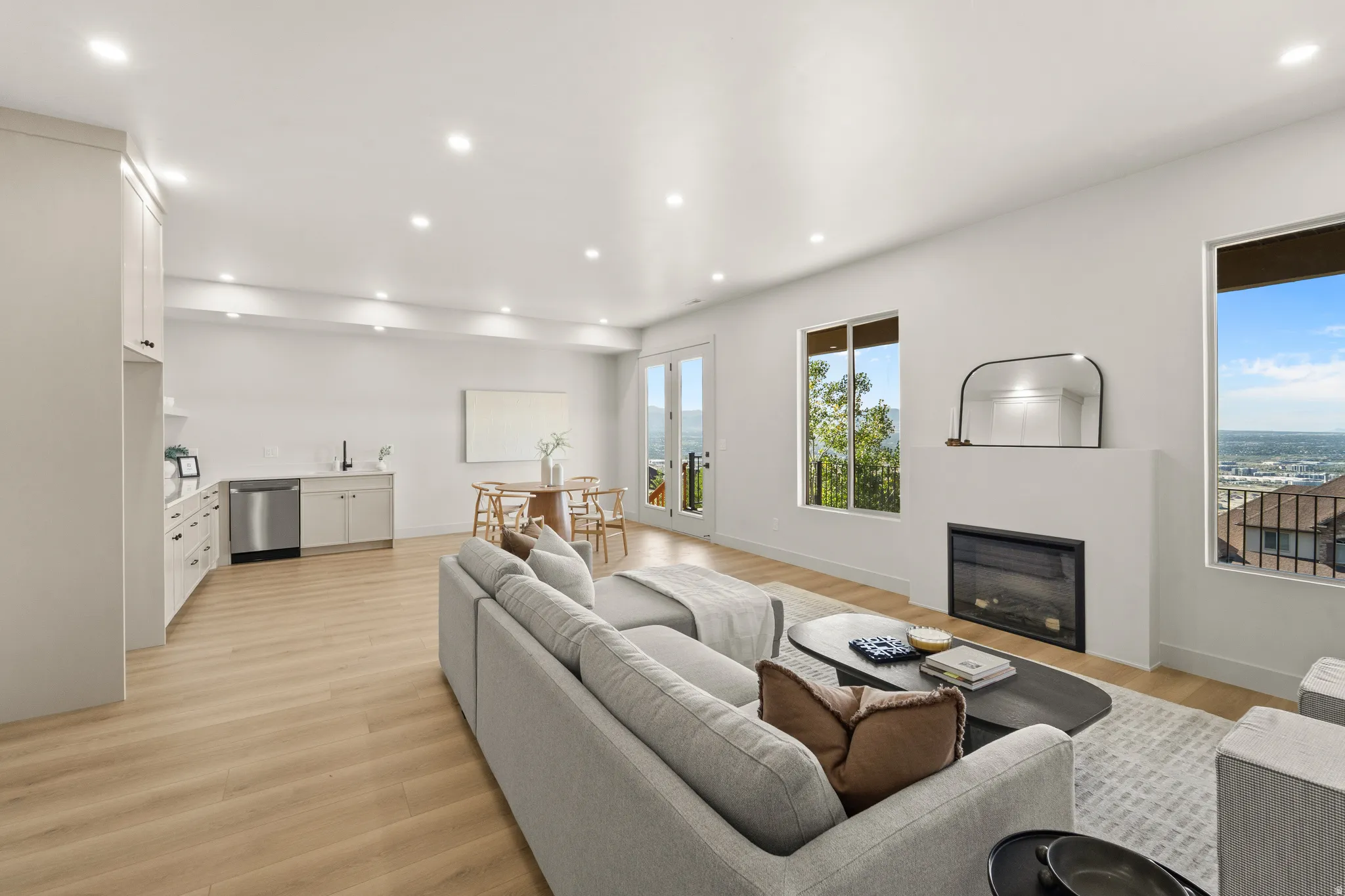 Recessed lighting, wood-finish flooring, a modern fireplace, and a built-in wet bar with stainless steel appliances