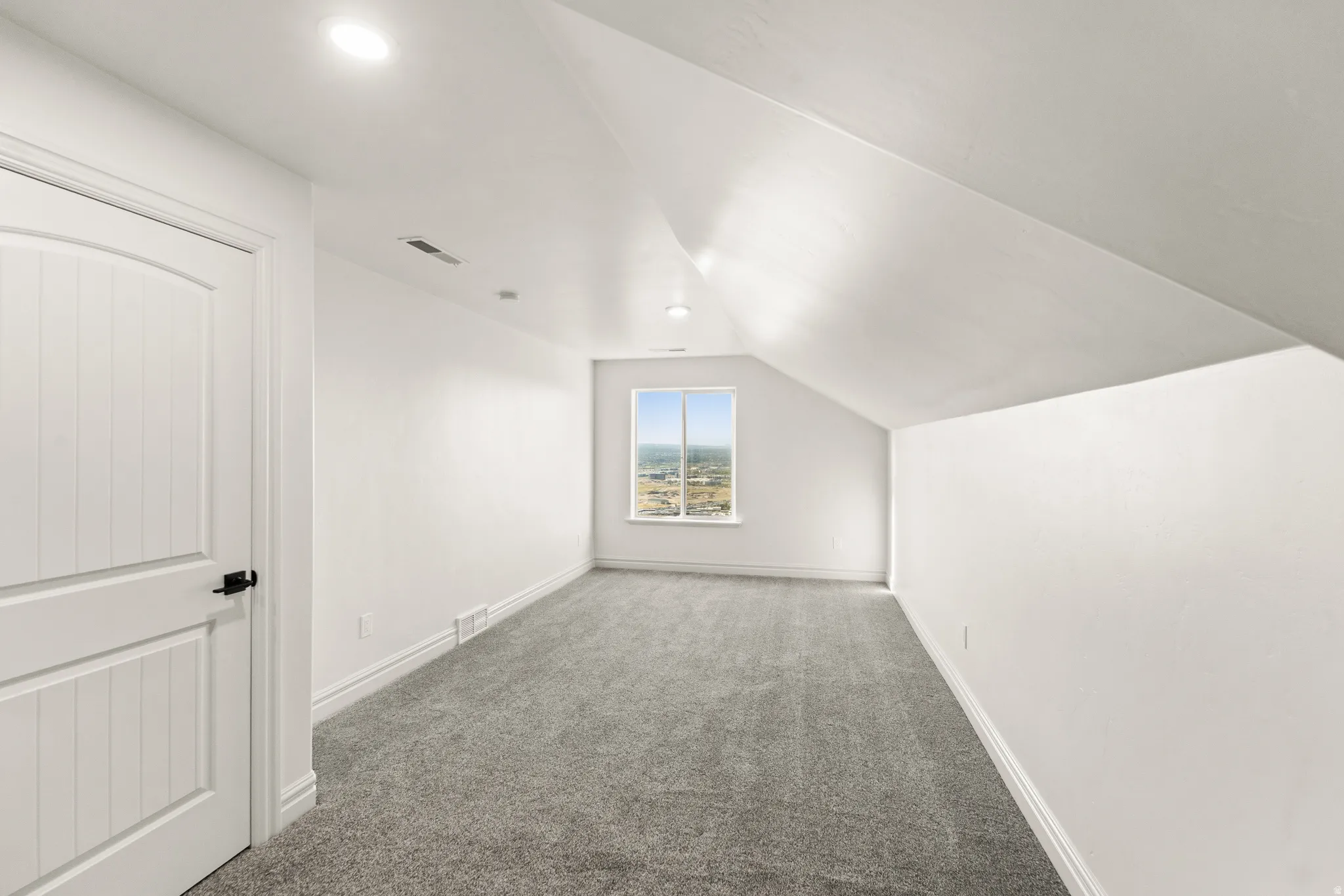 Carpeted room featuring a single window, recessed lighting, and a white paneled door with black hardware