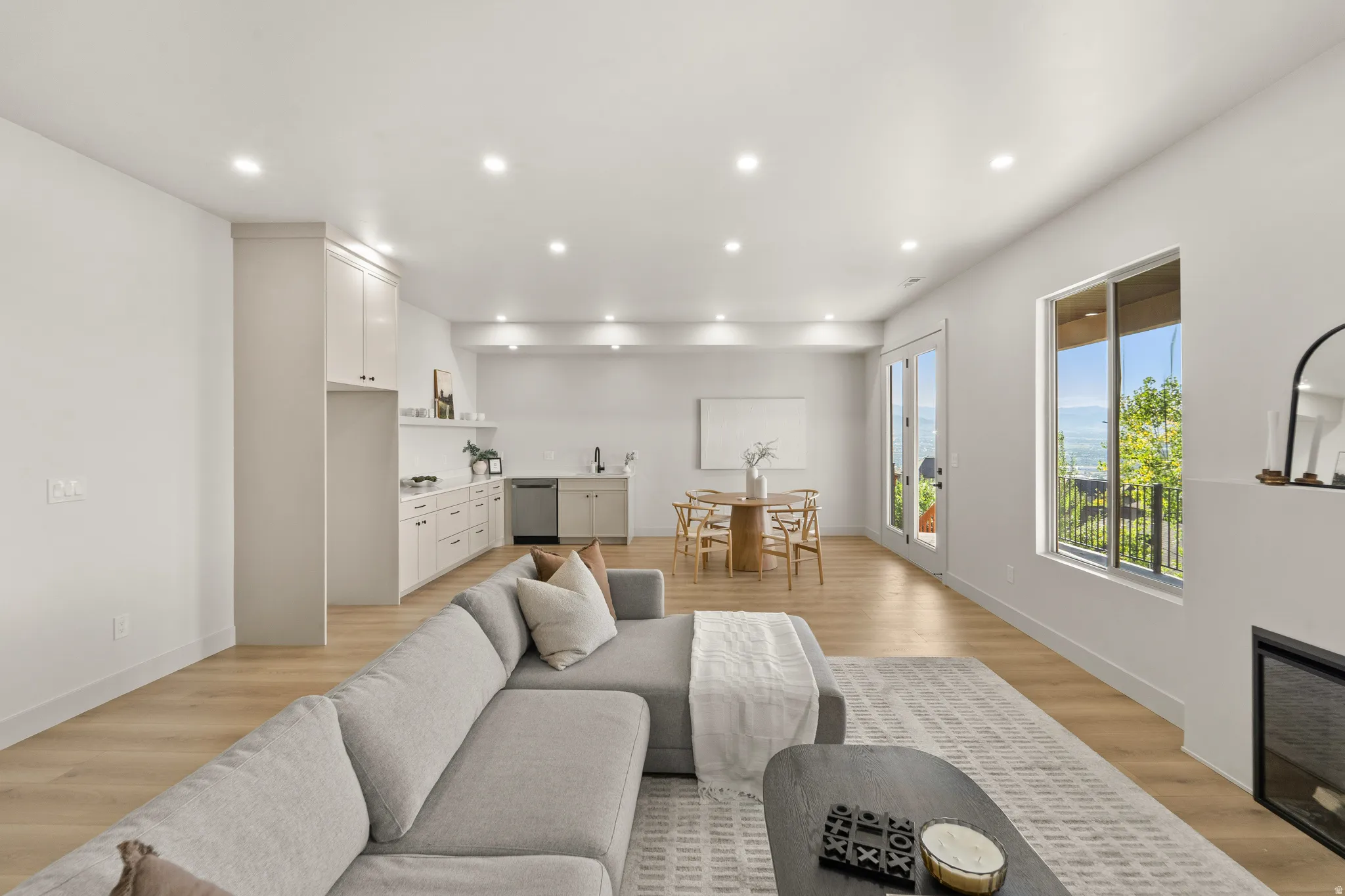Recessed lighting throughout, wood-finish flooring, two-panel glass French doors, large window with outdoor scenery, and a built-in fireplace