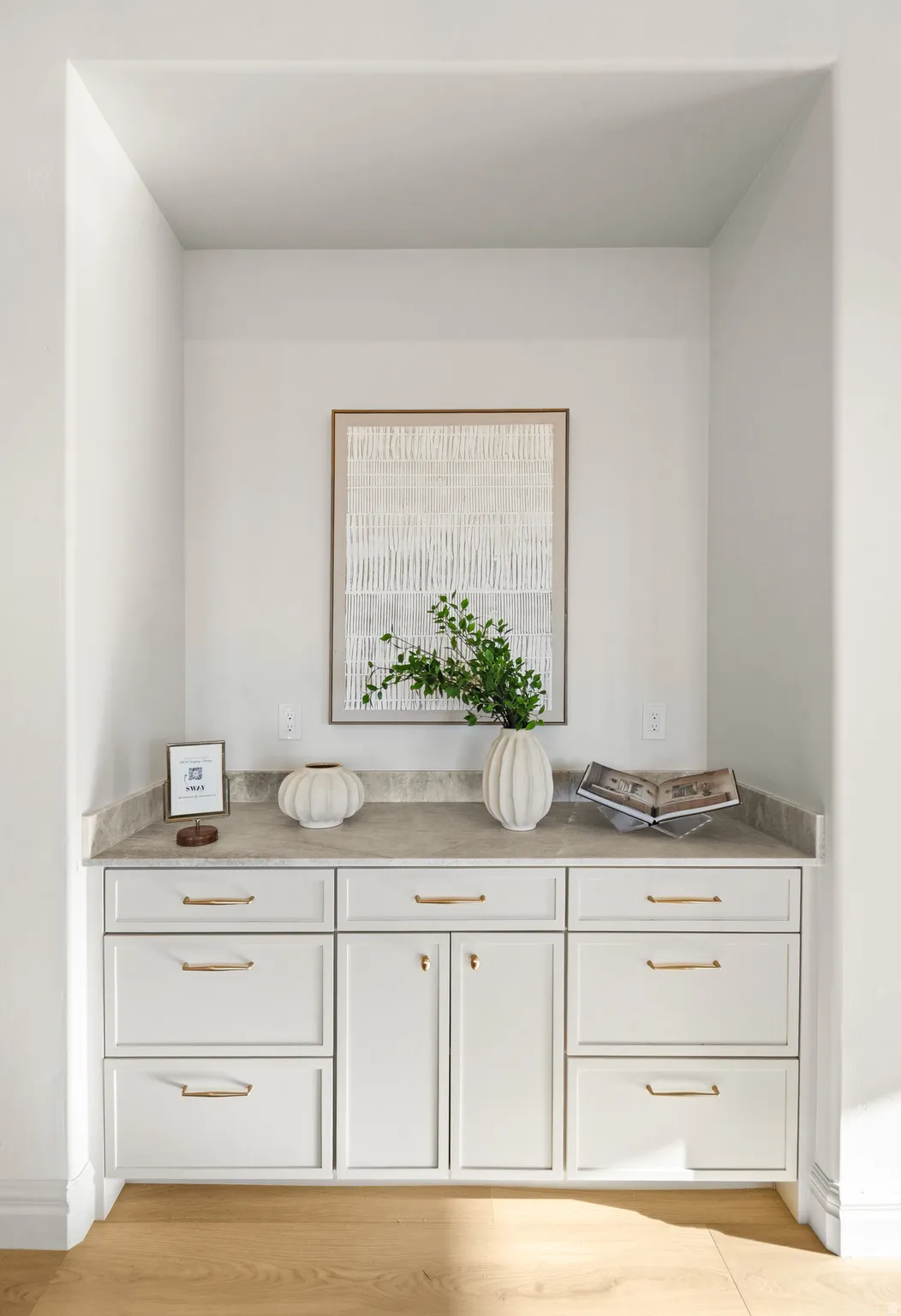 Built-in cabinetry with a stone-finish countertop, gold-tone hardware, and wood-finish flooring