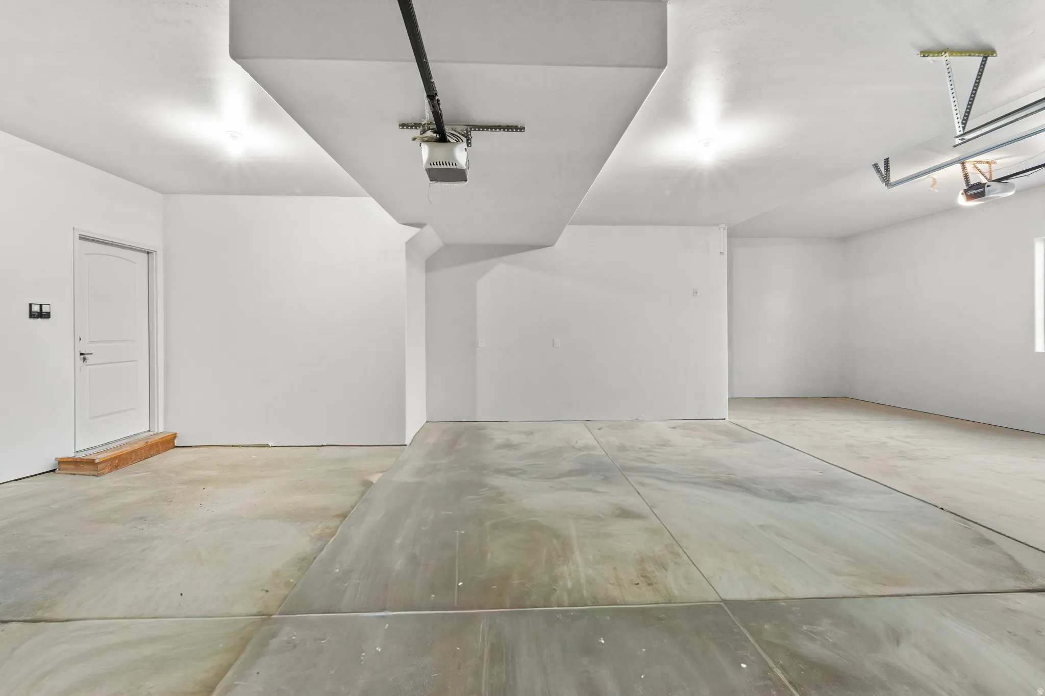 Open garage space with concrete flooring, recessed lighting, and a white paneled door
