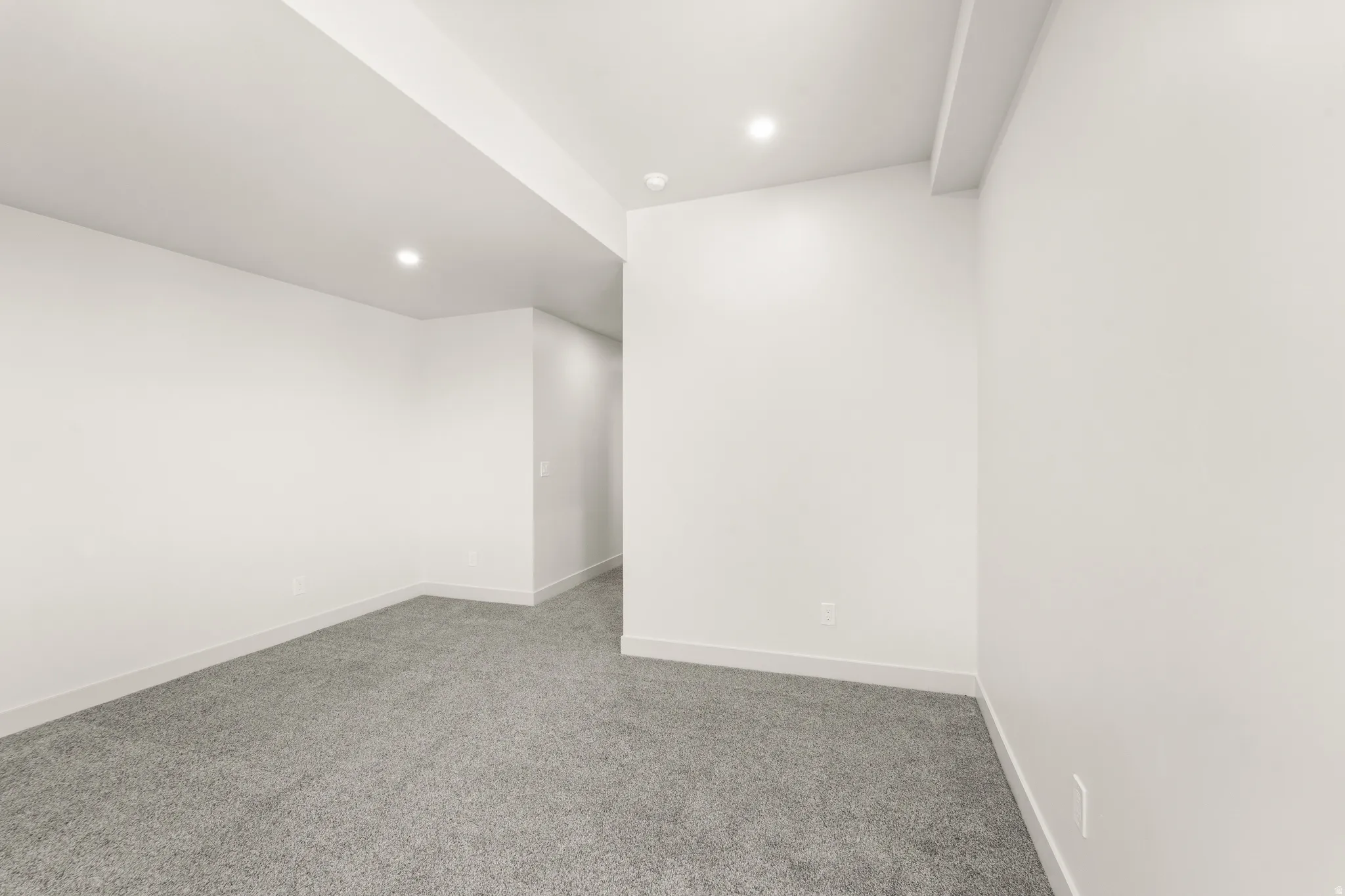 Recessed ceiling lighting, light gray wall-to-wall carpeting, white painted walls, and white trim