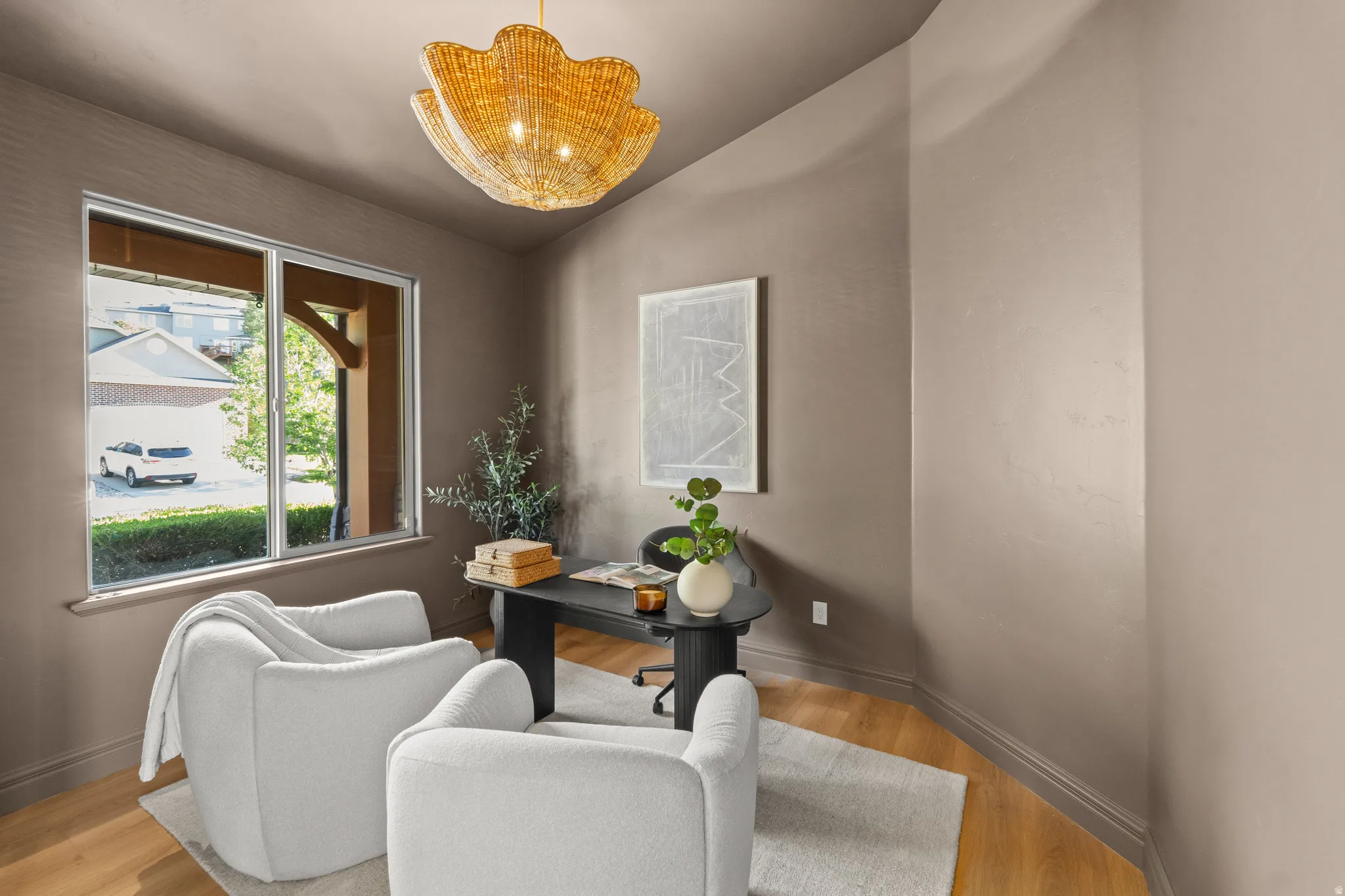 Recessed wall with a large window, light wood-finish flooring, and a unique pendant light fixture