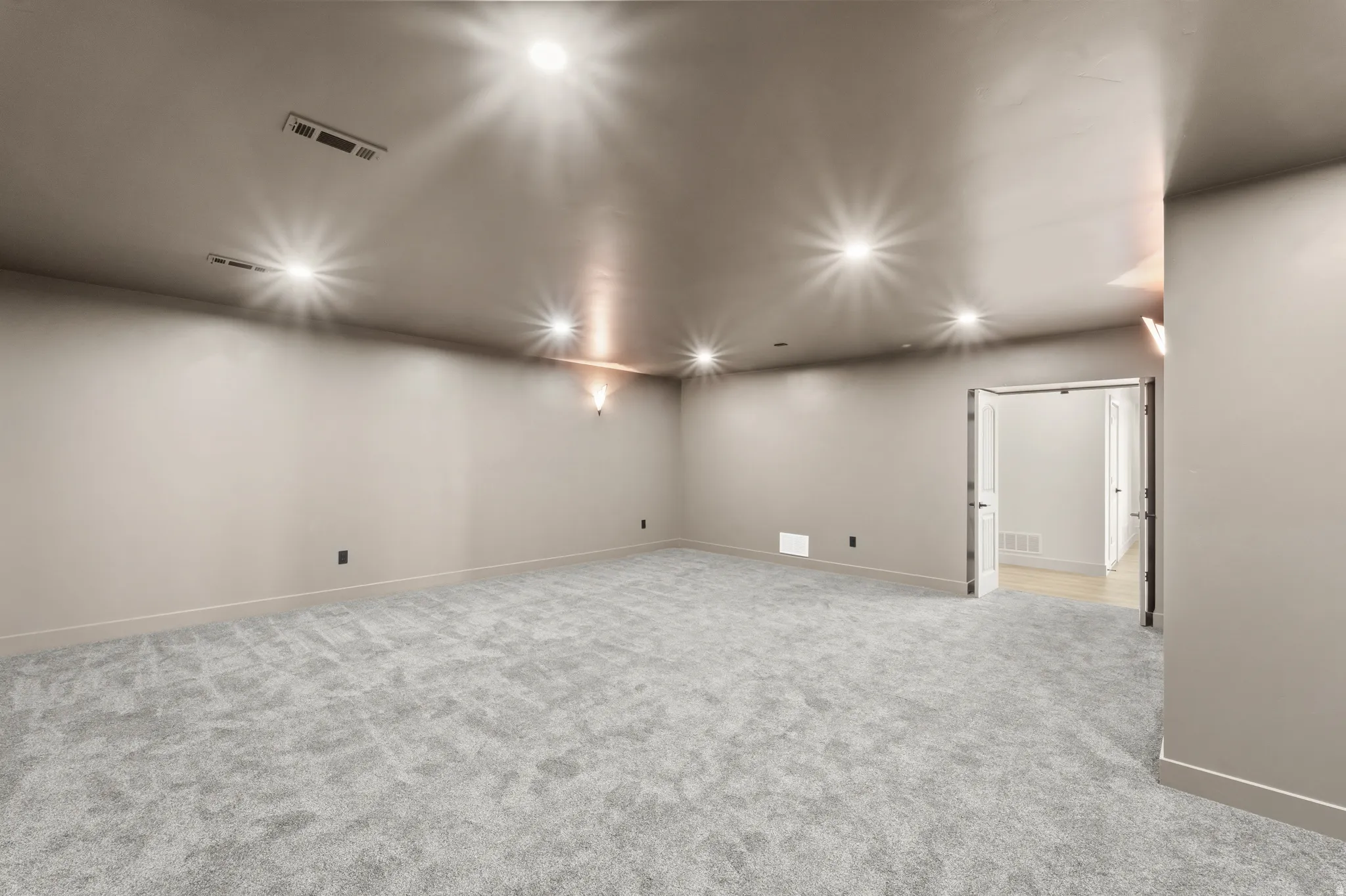 Expansive room with neutral carpeting, recessed ceiling lighting, and a double doorway