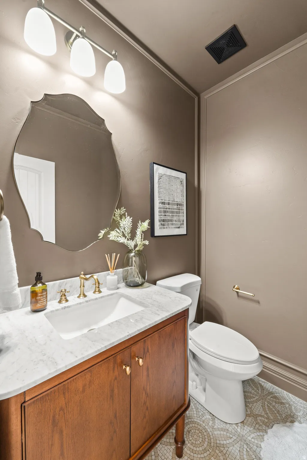 Wood-finish vanity with a white countertop and gold-tone faucet