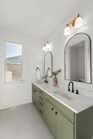 Dual vanity with a white countertop and integrated sinks, matte black faucets, and green cabinetry