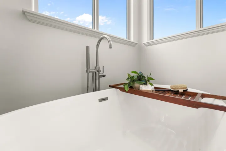 Freestanding soaking tub with a brushed nickel floor-mounted faucet and handheld shower sprayer