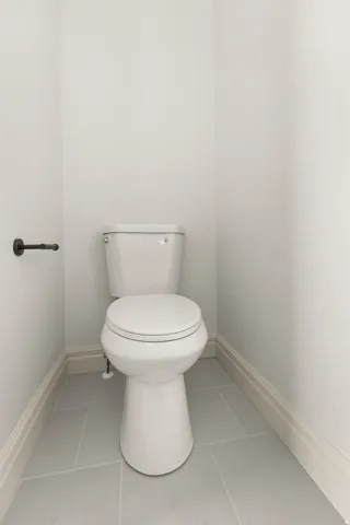 White toilet with gray tile flooring and white trim