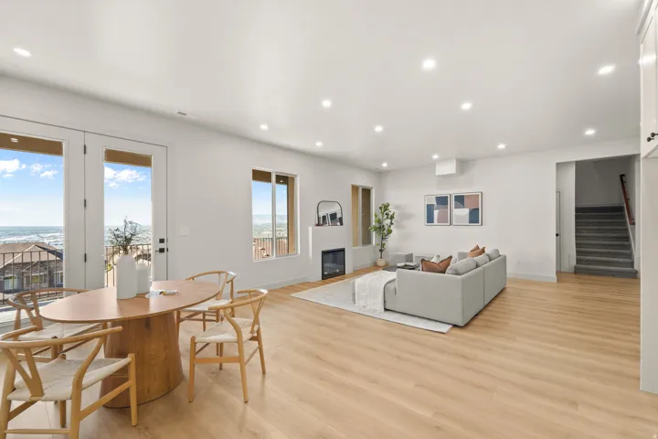 Open-concept living space with light wood-finish flooring, recessed lighting, and a modern fireplace