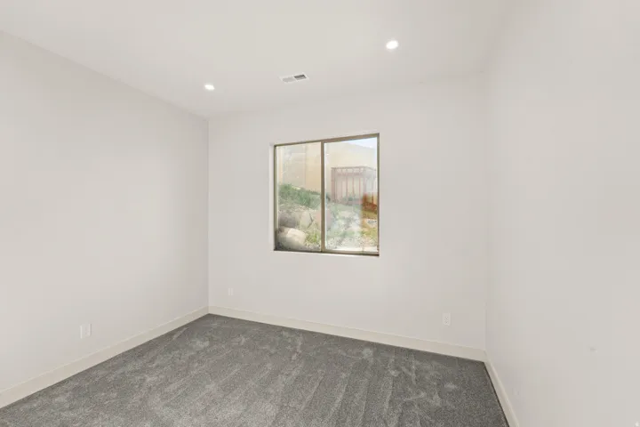 Recessed lighting, light-toned walls, and grey carpeting