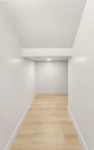 Recessed ceiling lighting, wood-finish flooring, white walls, and bright white trim
