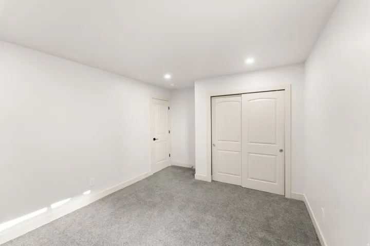 Recessed lighting, light gray carpeting, white walls, white paneled doors, and white trim