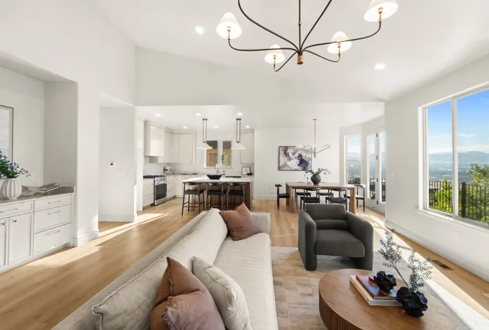 Vaulted ceilings with recessed lighting, wood-finish flooring, white cabinetry with built-in storage, and a large window providing expansive mountain and city scenery