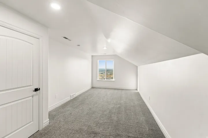 Carpeted room featuring a single window, recessed lighting, and a white paneled door with black hardware