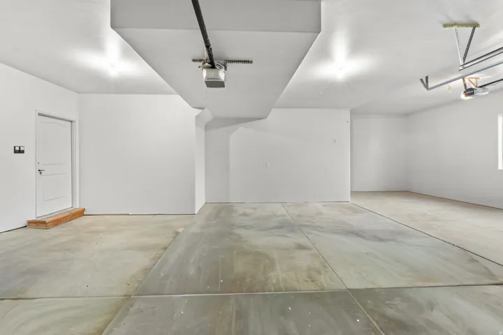 Open garage space with concrete flooring, recessed lighting, and a white paneled door