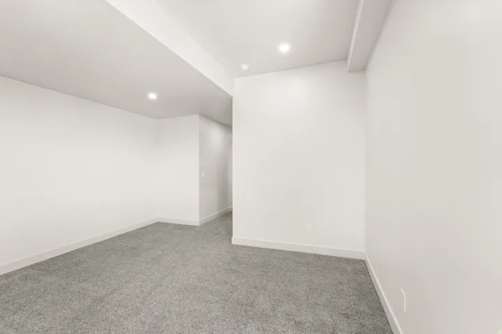 Recessed ceiling lighting, light gray wall-to-wall carpeting, white painted walls, and white trim