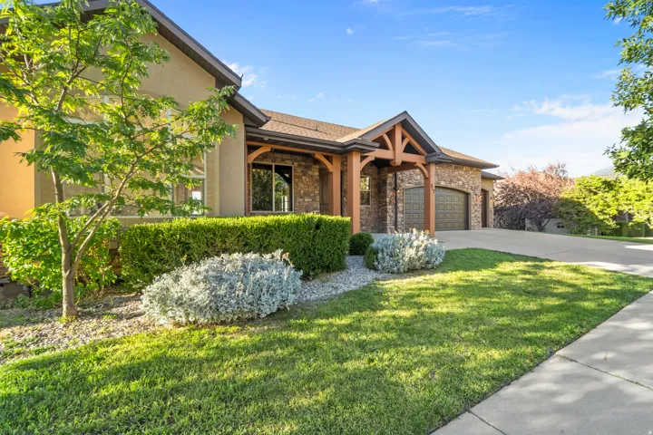 Stone and stucco exterior with exposed timber architectural accents, a paved driveway, and a two-car garage