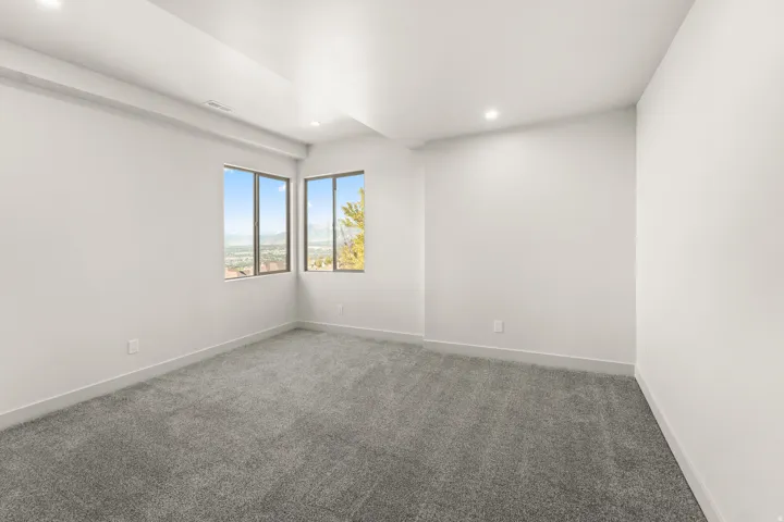 Recessed lighting illuminates the neutral gray carpeting and white painted walls