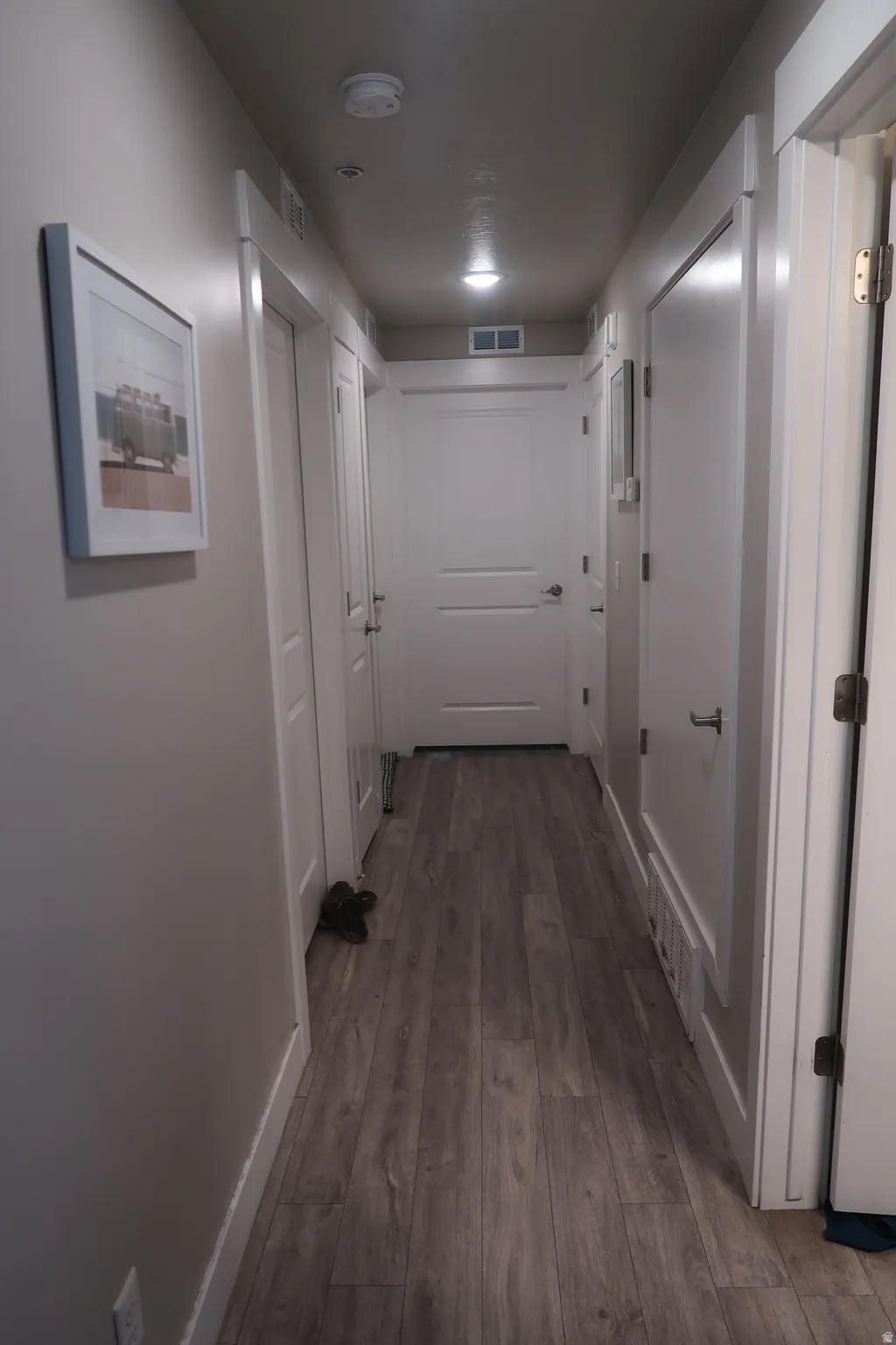 Wood-finish flooring throughout, multiple white panel doors with brushed nickel hardware, recessed ceiling lighting, and a neutral wall color