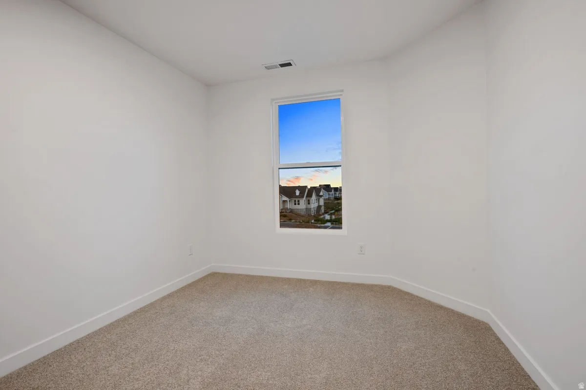 Neutral-toned carpeting, white walls, and a single window with white trim