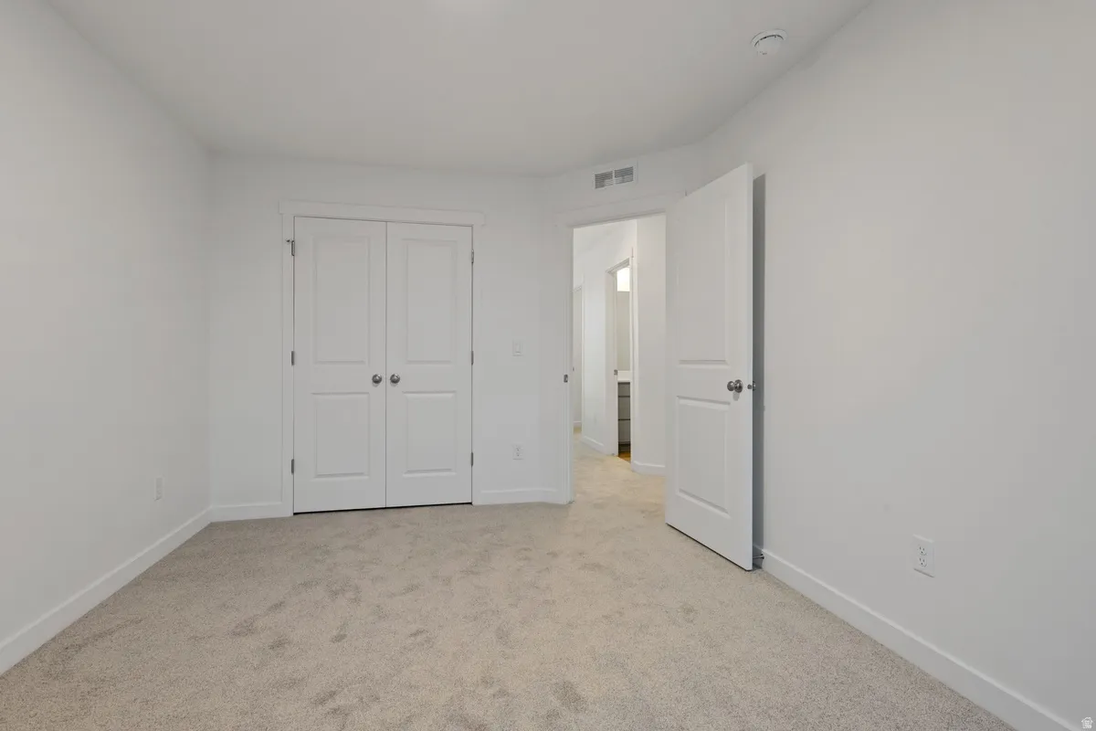 Neutral tone carpeted flooring with white baseboards, white walls, and a white ceiling