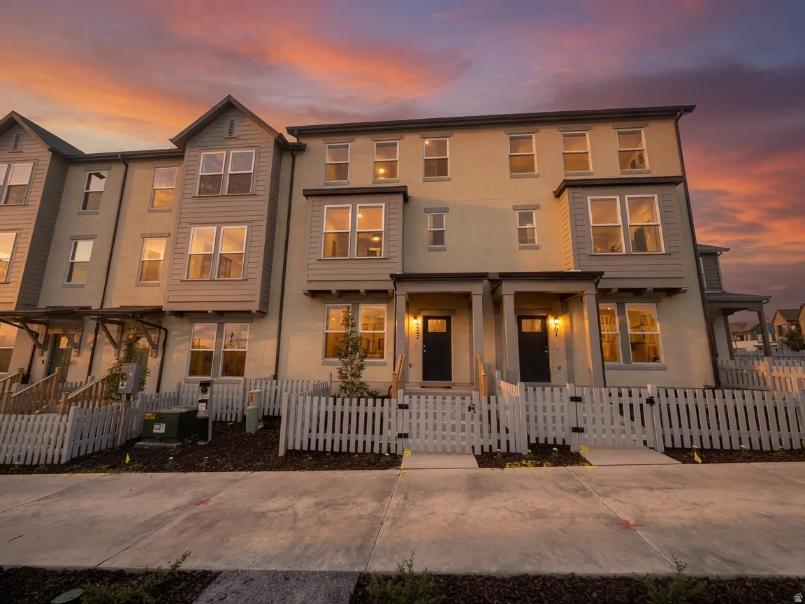 Three-story townhome with light-toned stucco and gray siding