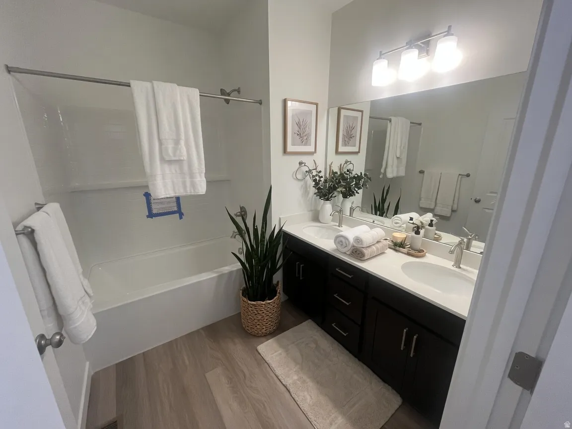 Double vanity with white countertop, dark wood-finish cabinetry, chrome fixtures, and wood-finish flooring
