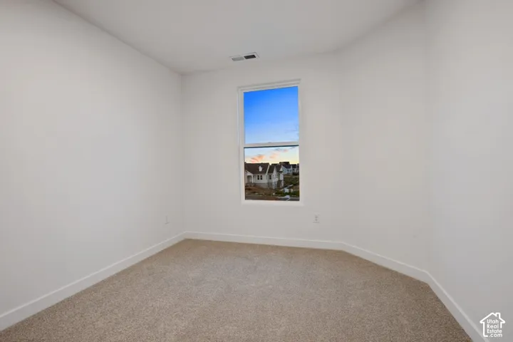 Neutral-toned carpeting, white walls, and a single window with white trim