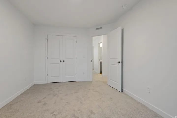 Neutral tone carpeted flooring with white baseboards, white walls, and a white ceiling