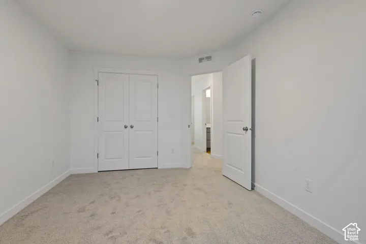 Neutral tone carpeted flooring with white baseboards, white walls, and a white ceiling