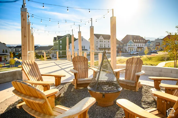 Outdoor patio with string lighting, a built-in fire pit, and a surrounding gravel surface