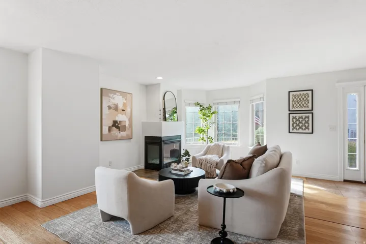 Living area featuring wood-finish flooring, a contemporary fireplace, and a bay window