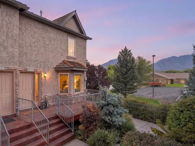 Stucco exterior with stone accent, dual entry doors with sidelights, tiered wood deck with metal railings, and bay window feature