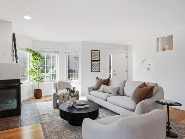 Recessed lighting illuminates this bright living space featuring a bay window, built-in fireplace, and hardwood-finish flooring