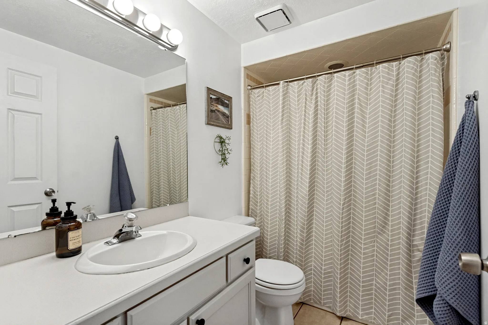 White vanity with integrated sink, chrome faucet, and overhead bar lighting
