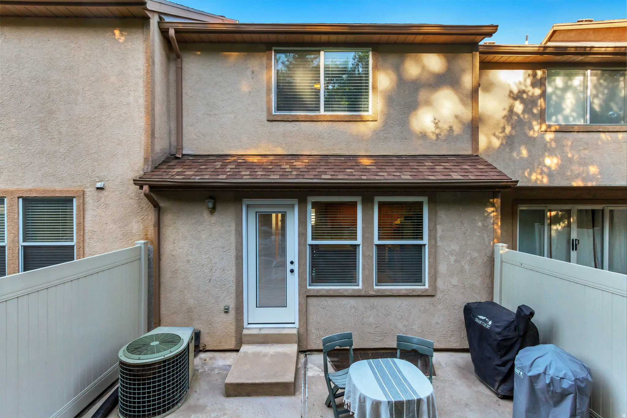 Private patio area with stucco exterior, a covered entryway, and white fencing