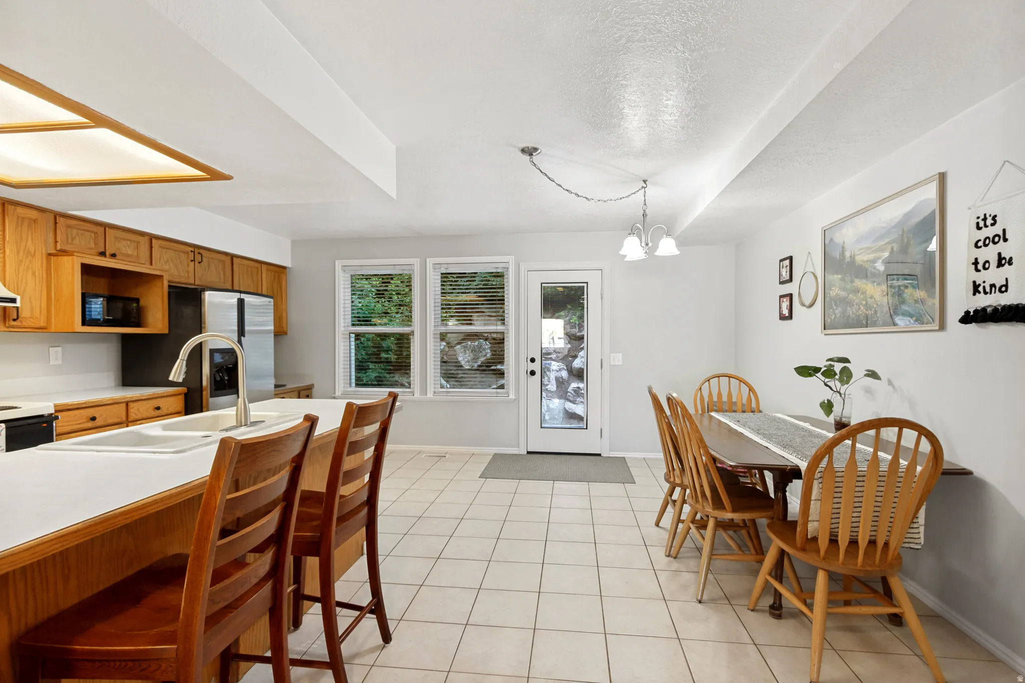 Kitchen featuring wood cabinetry, stainless steel appliances, a kitchen island with a double basin sink, and tile flooring