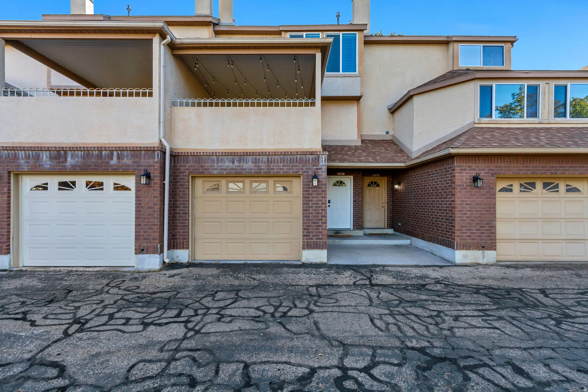 Brick and stucco exterior with multiple windows, two distinct front entry doors, and two garage doors