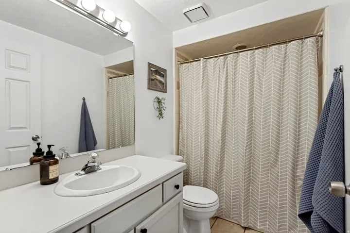 White vanity with integrated sink, chrome faucet, and overhead bar lighting
