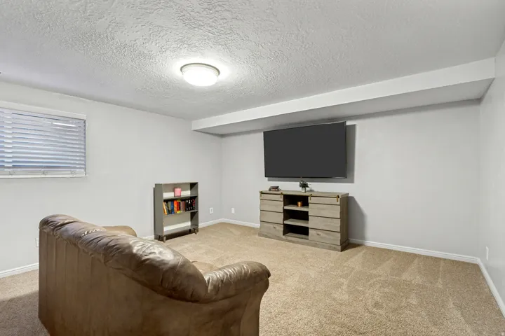 Recessed window with blinds, overhead flush mount lighting, wall-mounted display, and carpeted flooring