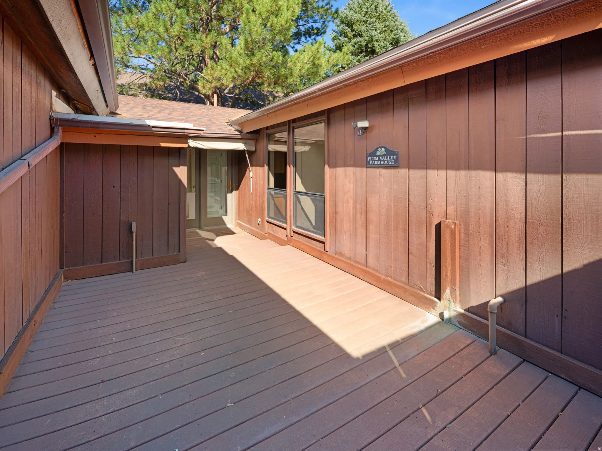 Expansive wood-finish deck with vertical wood siding and a transom window