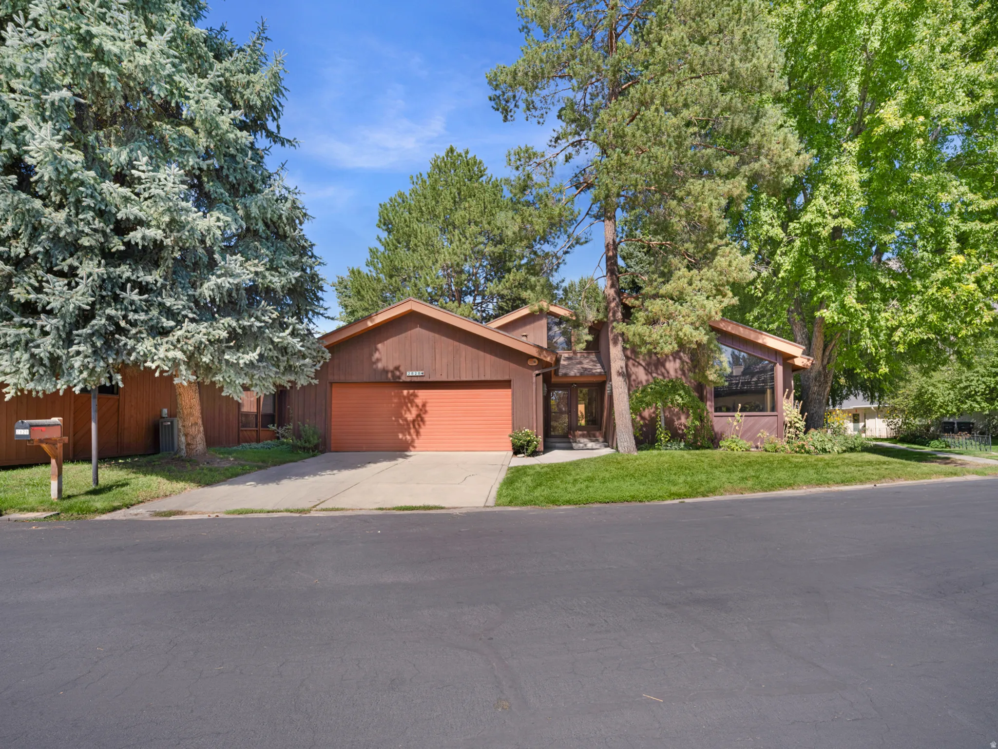 Brown wood-sided exterior with a sloped roofline, attached garage, and prominent front entry