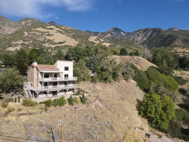 Multi-level residence featuring a tiered deck, brick chimney, and a light-colored stucco exterior