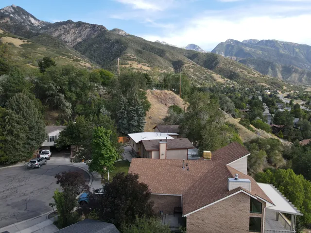 Mountainous backdrop with surrounding mature trees and hillside landscaping