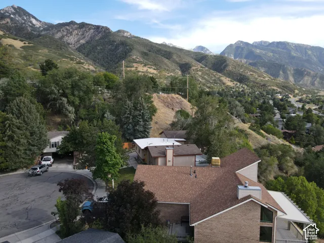 Mountainous backdrop with surrounding mature trees and hillside landscaping