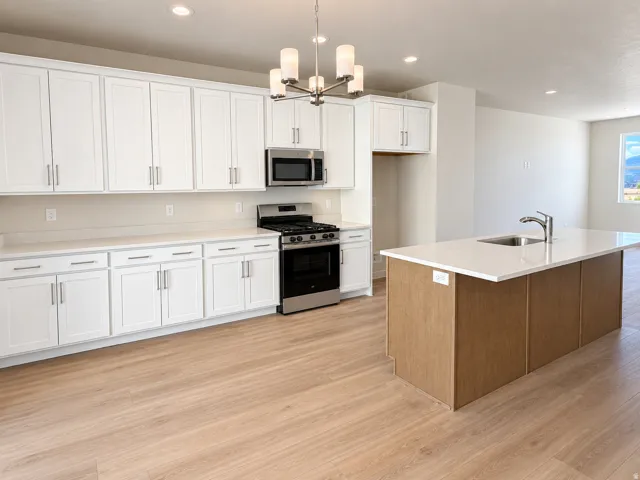 Kitchen featuring white shaker cabinetry, stainless steel appliances, light-toned countertops, and wood-finish flooring