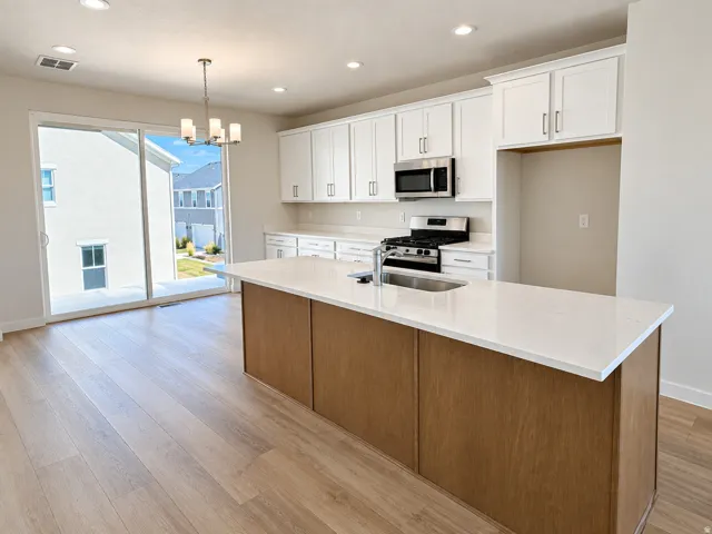 Kitchen with large island, gas stove, dining area and covered deck with a sliding glass door