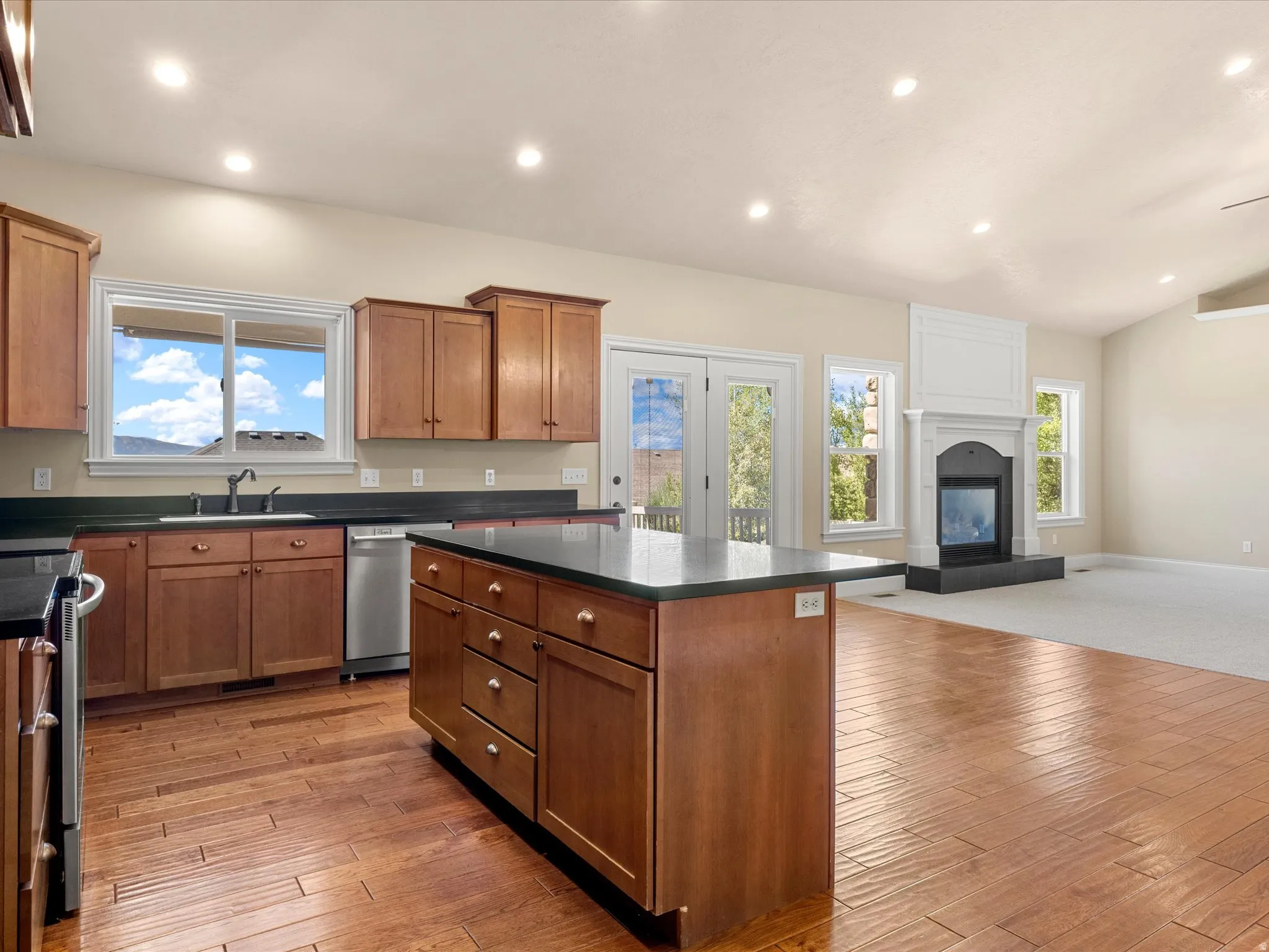 Open-concept kitchen featuring wood-finish flooring, recessed lighting, a central island, and wood cabinetry