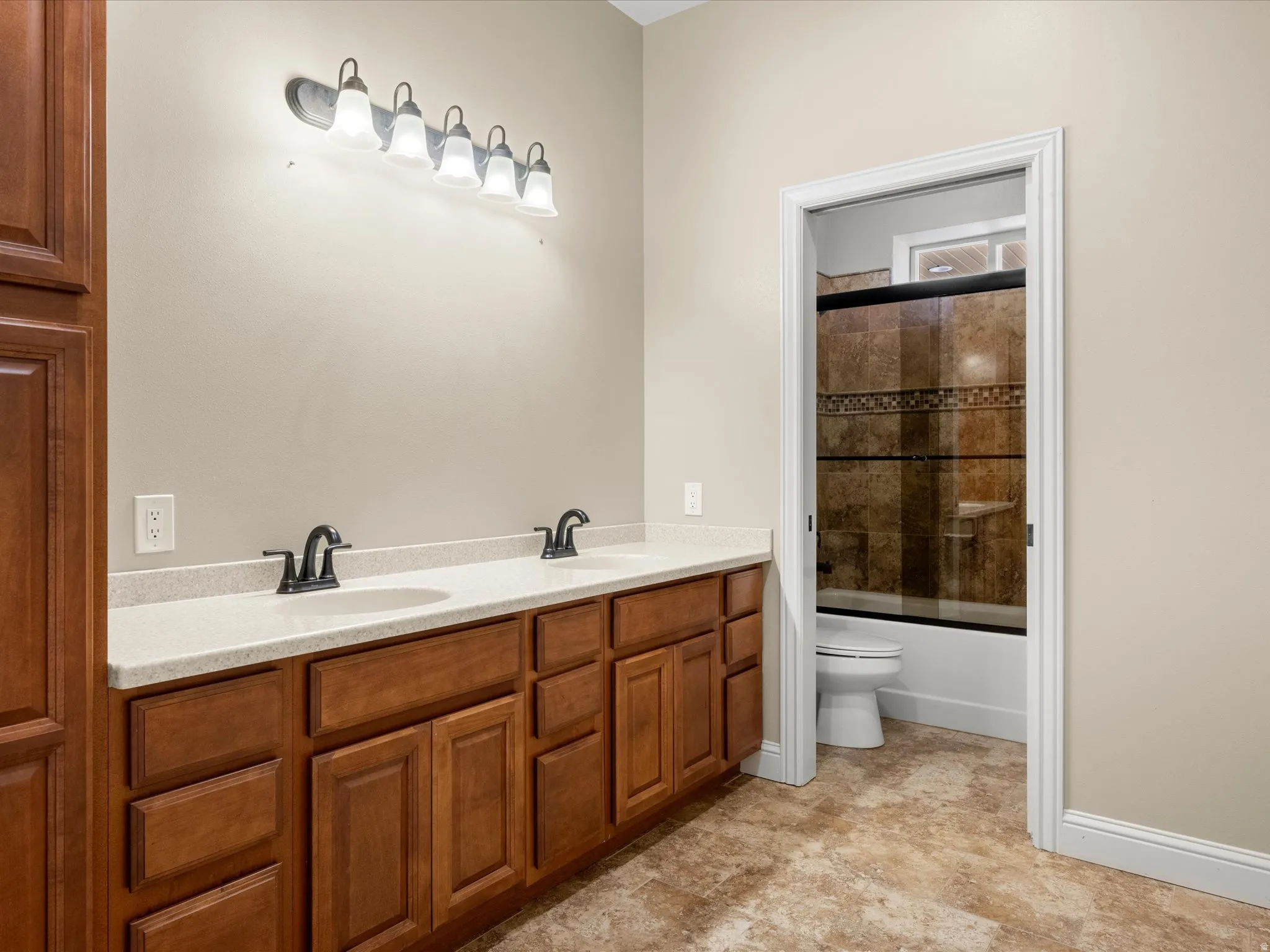 Dual vanity with light-colored countertop, wood-finish cabinetry, and matte black fixtures